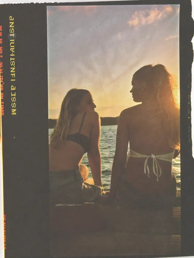 two friends on a lake dock at sunset