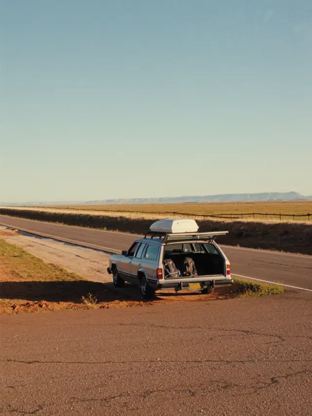 an old station wagon parked on an empty desert highway