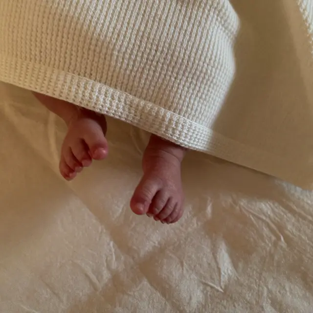 a newborn's tiny feet peeking out of a knit blanket